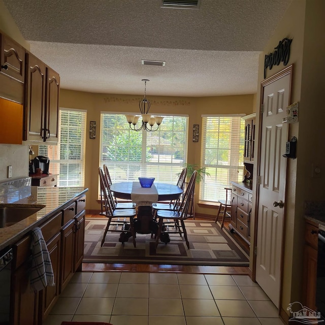 dining room featuring light tile patterned floors, visible vents, a textured ceiling, and an inviting chandelier