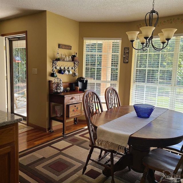 dining room with a chandelier, light wood-style flooring, and a textured ceiling
