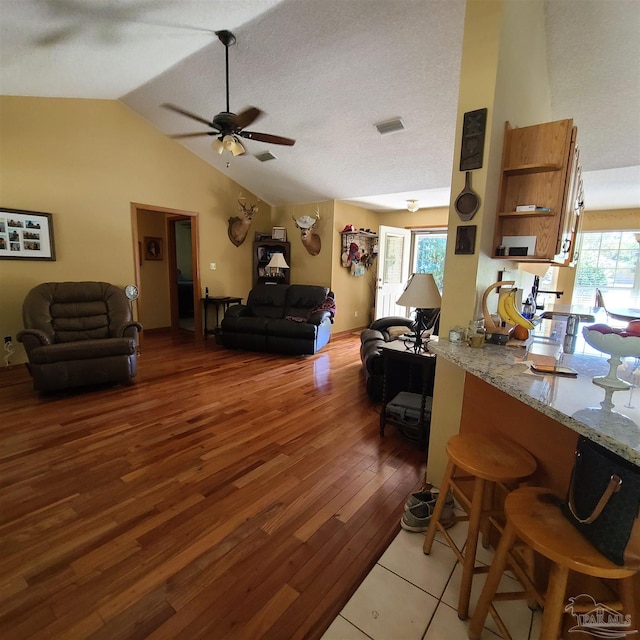 living room with light wood finished floors, visible vents, high vaulted ceiling, and ceiling fan