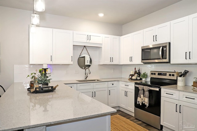 9668 Nature Creek Blvd, Pensacola, FL 32526 - kitchen with stainless steel appliances, a peninsula, white cabinetry, wood finished floors, and decorative backsplash