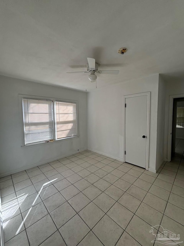 tiled empty room featuring ceiling fan