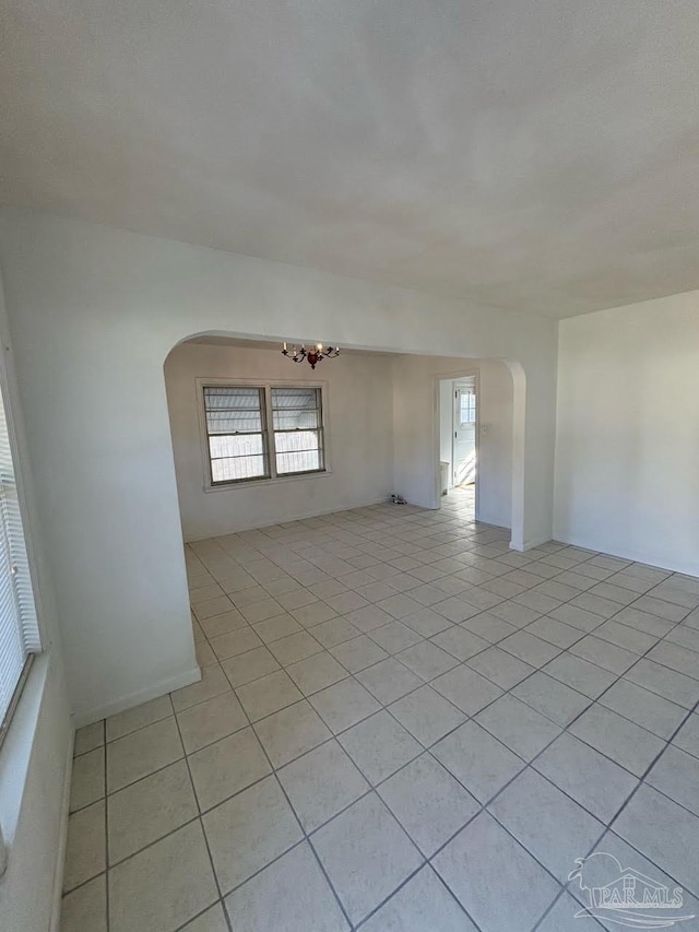 tiled empty room with an inviting chandelier