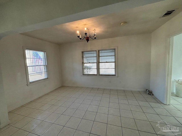 empty room featuring light tile patterned floors and a notable chandelier