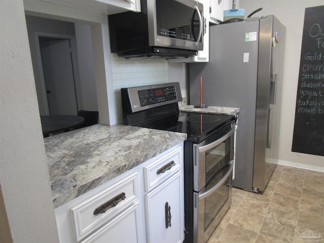 kitchen featuring appliances with stainless steel finishes, white cabinetry, light stone countertops, and decorative backsplash