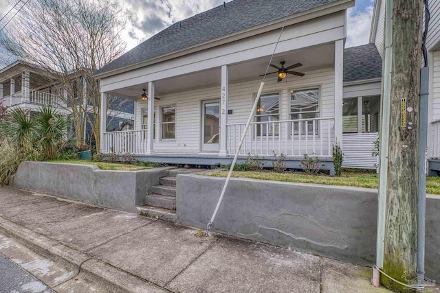 property entrance featuring a shingled roof, covered porch, and ceiling fan