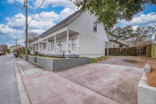 view of property exterior with ceiling fan, fence, and a porch