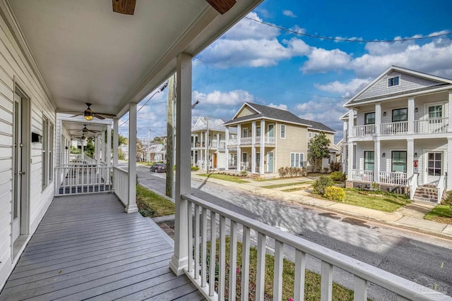 wooden deck featuring a porch, a ceiling fan, and a residential view