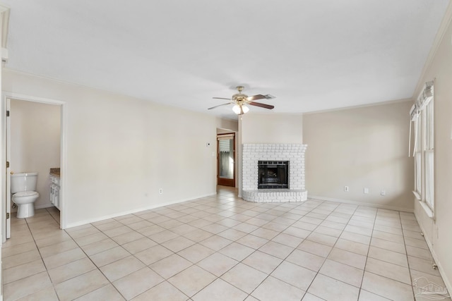 unfurnished living room with light tile patterned floors, baseboards, ceiling fan, crown molding, and a fireplace