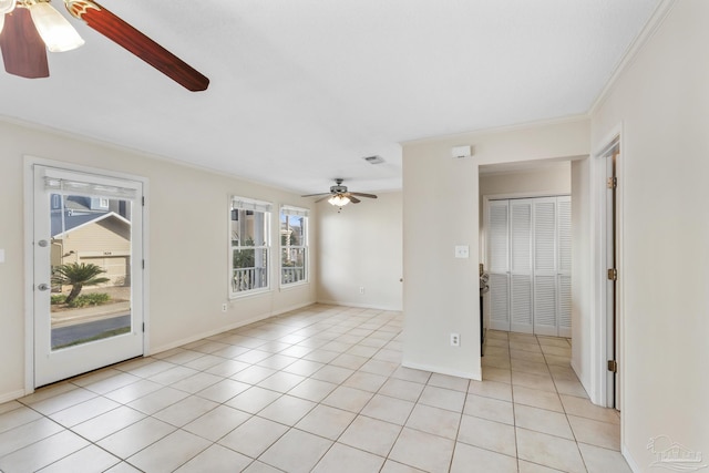 unfurnished room with ornamental molding, ceiling fan, baseboards, and light tile patterned floors