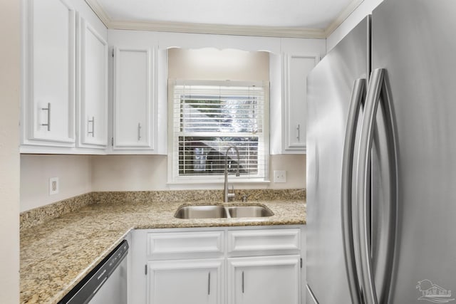 kitchen with light stone counters, white cabinetry, stainless steel appliances, and a sink