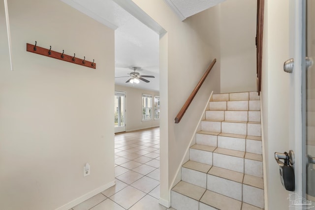 staircase with tile patterned flooring, ceiling fan, a textured ceiling, and baseboards