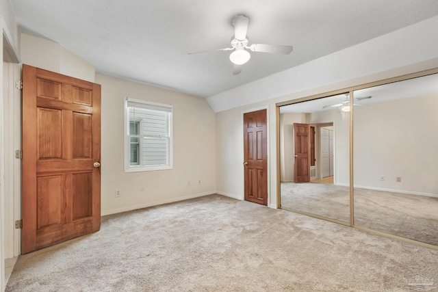 unfurnished bedroom with baseboards, vaulted ceiling, a closet, and light colored carpet