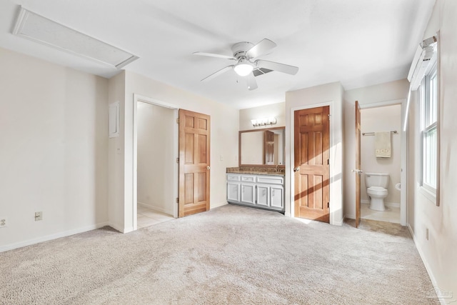 unfurnished bedroom featuring ceiling fan, connected bathroom, light carpet, baseboards, and attic access