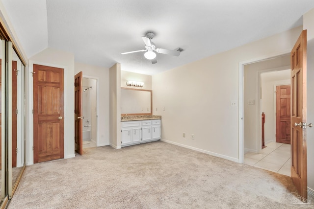 unfurnished bedroom with light tile patterned floors, ensuite bath, baseboards, and light colored carpet