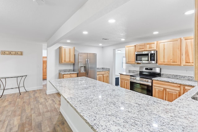 kitchen featuring light stone countertops, visible vents, light brown cabinets, and appliances with stainless steel finishes