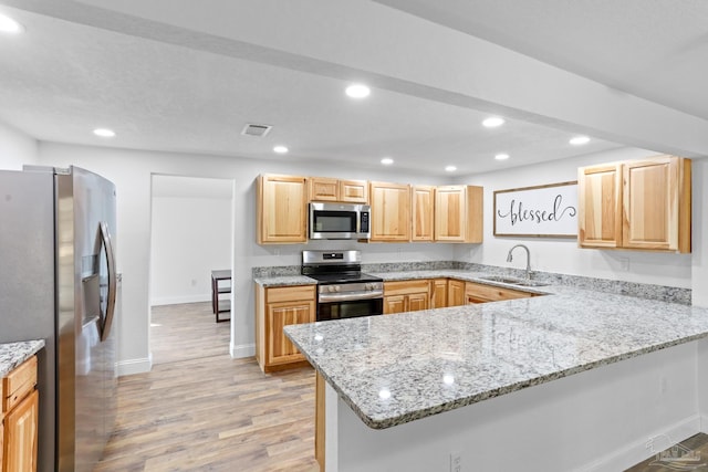 kitchen with a peninsula, visible vents, stainless steel appliances, and a sink