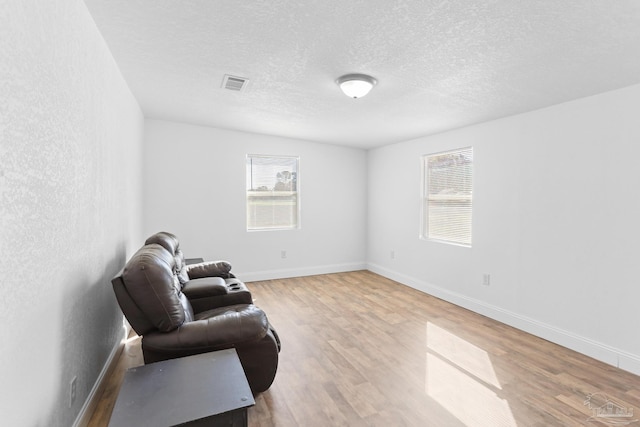 sitting room featuring a textured ceiling, wood finished floors, visible vents, and baseboards