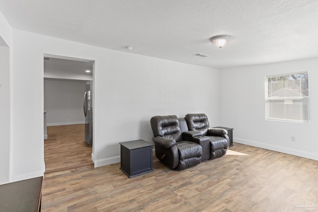 living area with a textured ceiling, baseboards, and wood finished floors