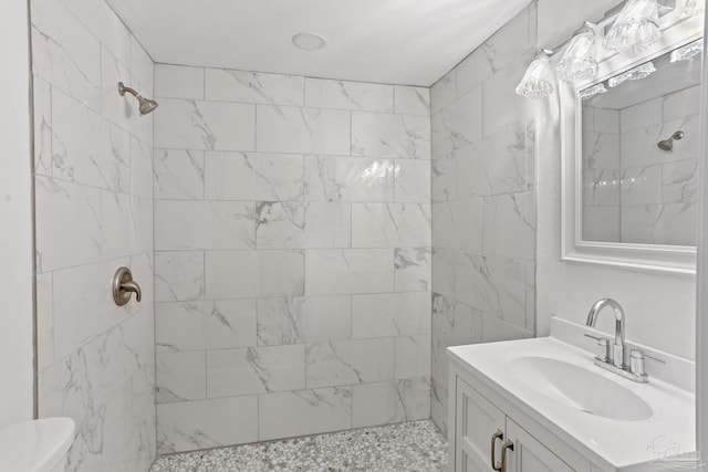 bathroom featuring toilet, a tile shower, and vanity