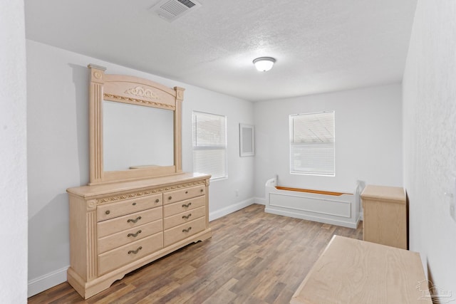 bedroom featuring visible vents, multiple windows, and wood finished floors