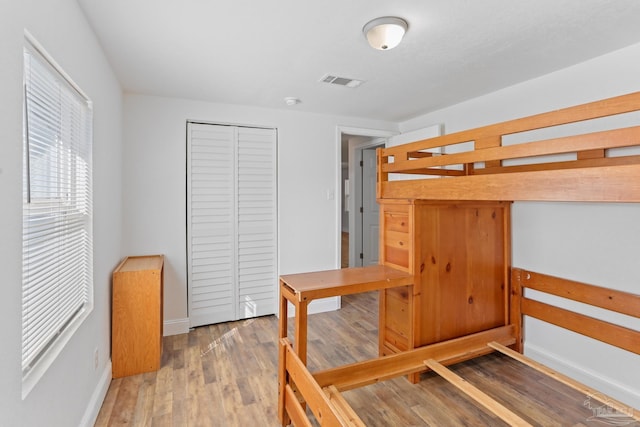 bedroom with baseboards, a closet, visible vents, and wood finished floors