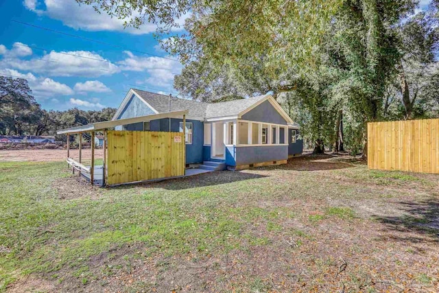 rear view of house featuring a yard, fence, and stucco siding