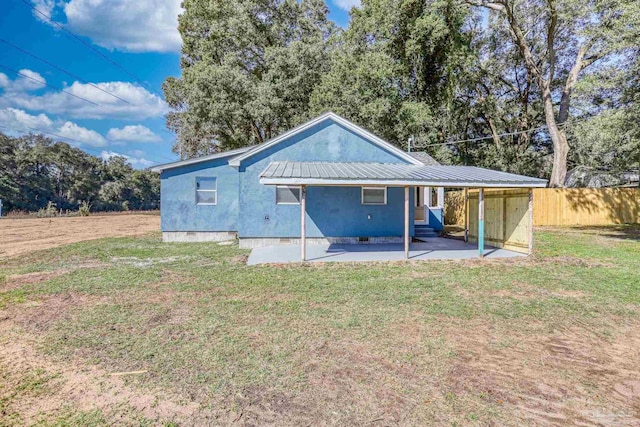 rear view of property featuring metal roof, crawl space, a patio area, and a lawn