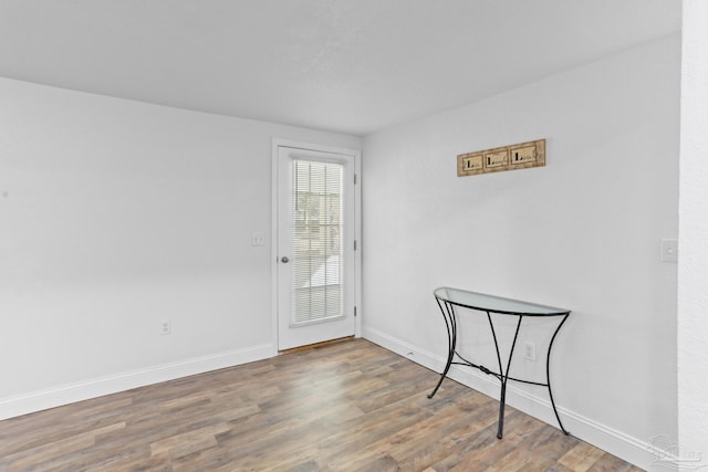 doorway with baseboards and wood finished floors