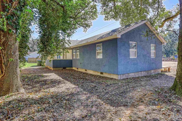 view of property exterior with roof with shingles, crawl space, and stucco siding