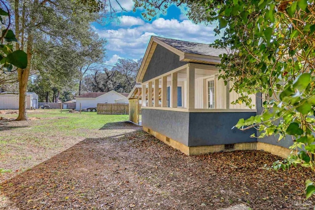 view of side of home featuring an outbuilding, crawl space, fence, and a storage unit