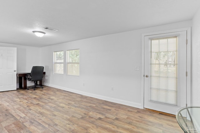 office space with baseboards, visible vents, and light wood finished floors