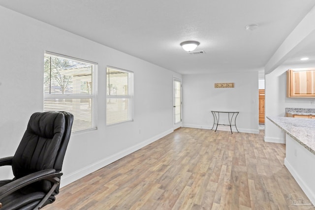 office area featuring light wood-type flooring, visible vents, and baseboards