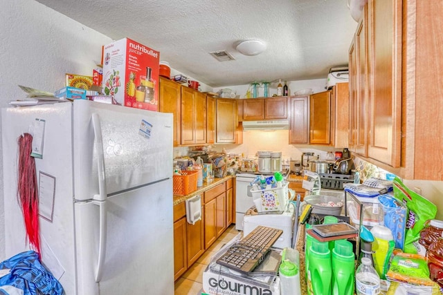 kitchen featuring white appliances, a textured ceiling, and light tile patterned floors