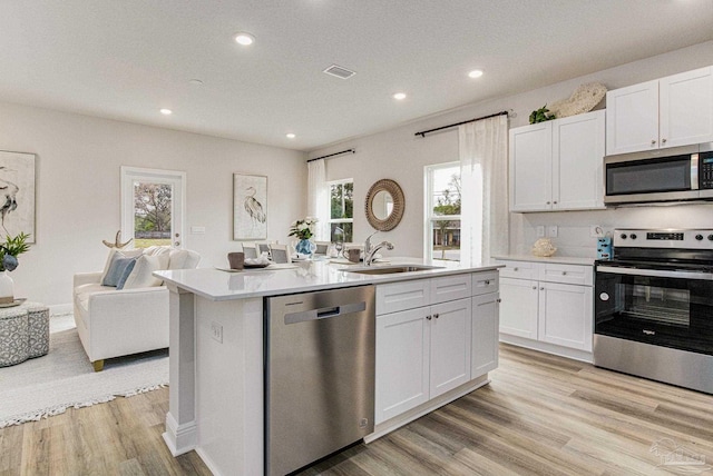 kitchen featuring sink, appliances with stainless steel finishes, a kitchen island with sink, plenty of natural light, and white cabinets