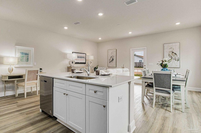 kitchen with white cabinetry, dishwasher, sink, and a center island with sink