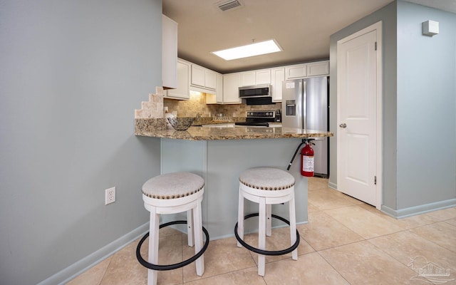 kitchen featuring light tile patterned floors, appliances with stainless steel finishes, and dark stone counters