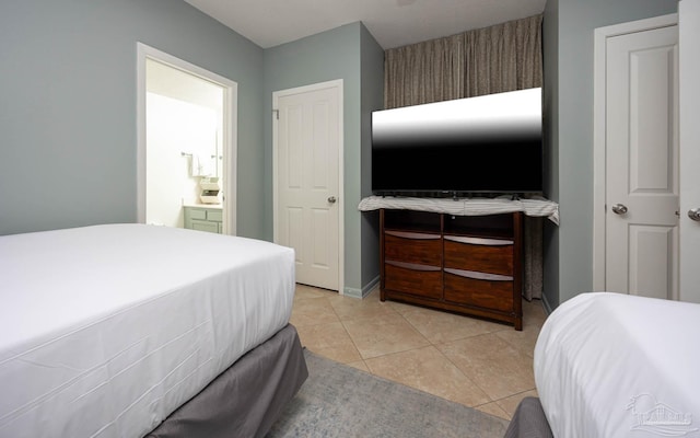 bedroom featuring connected bathroom, baseboards, and light tile patterned floors