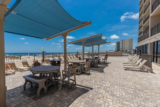 view of patio / terrace featuring a water view, a view of the beach, and outdoor dining space