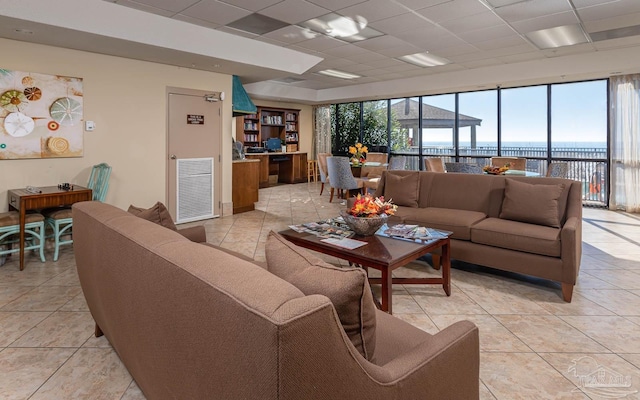 living area with light tile patterned floors, visible vents, and a drop ceiling