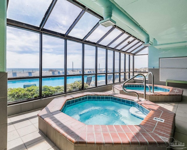 view of swimming pool featuring a lanai, an indoor hot tub, and a water view