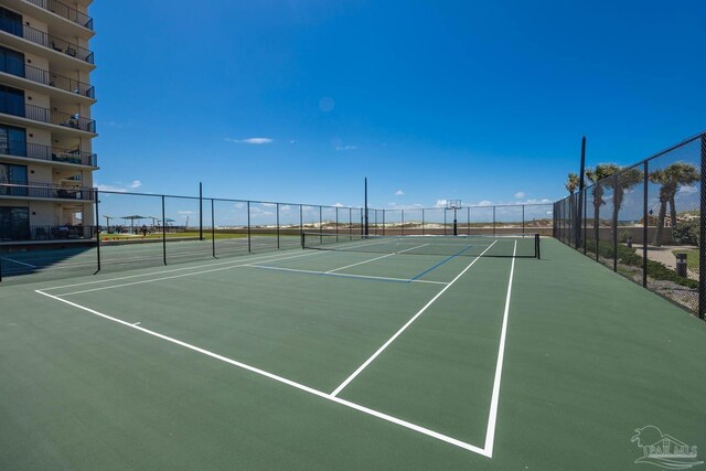 view of tennis court featuring community basketball court and fence