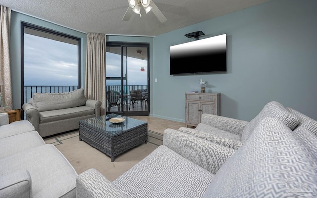 living room with a textured ceiling, ceiling fan, tile patterned floors, and baseboards