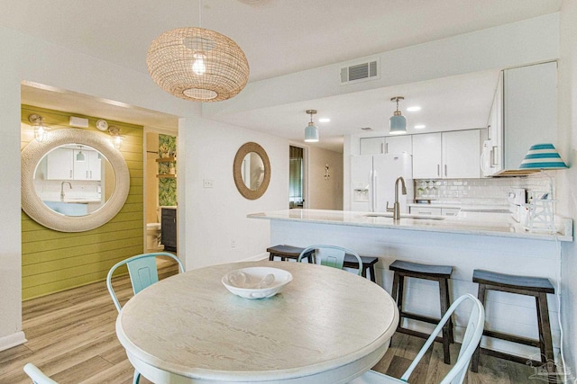 dining area with wooden walls, light hardwood / wood-style floors, and sink