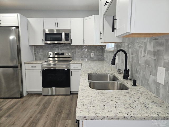 kitchen with tasteful backsplash, stainless steel appliances, hardwood / wood-style floors, sink, and white cabinetry