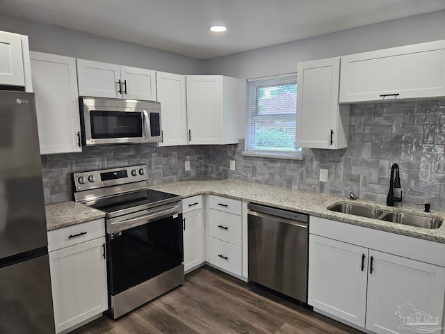 kitchen with tasteful backsplash, stainless steel appliances, sink, white cabinetry, and dark hardwood / wood-style flooring