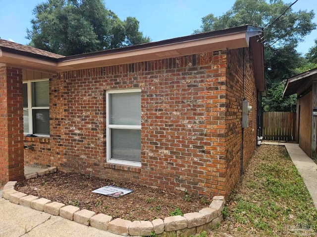 view of side of home with fence and brick siding