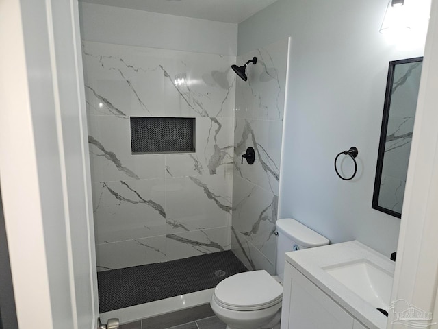 bathroom with vanity, a tile shower, tile patterned flooring, and toilet