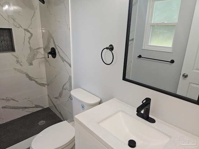 bathroom with toilet, vanity, and a tile shower