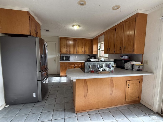 5325 Bob Sikes Blvd, Jay, FL 32565 - kitchen with stainless steel fridge, brown cabinets, black microwave, a peninsula, and light tile patterned floors