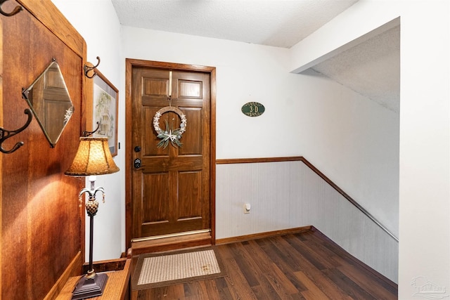 foyer with a textured ceiling, dark hardwood / wood-style flooring, wood walls, and beamed ceiling